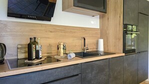 Eine moderne Küche mit Einbauofen, Mikrowelle und großem Flachbildfernseher, der über der Arbeitsfläche angebracht ist.