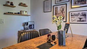 Ein Essbereich mit einem Holztisch, Stühlen, einer Blumenvase und gerahmten Bildern an der Wand.