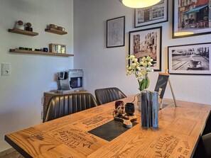 Ein Essbereich mit einem Holztisch, Stühlen, einer Blumenvase und gerahmten Bildern an der Wand.
