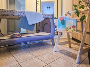 Ein Zimmer mit einer blauen Schlafcouch, einem kleinen Bücherregal und einer Pflanze.