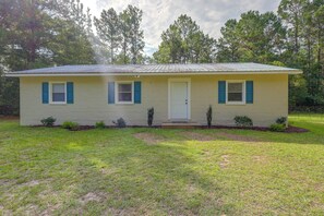 A single-story house with a front door, two windows with shutters, and a small porch area. - Quiet Country Living Near Whiteville (Whiteville)