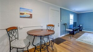 A dining area with a round table and four chairs, a painting on the wall, and a blue accent wall. - Quiet Country Living Near Whiteville (Whiteville)