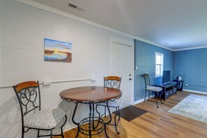 A dining area with a round table and four chairs, a painting on the wall, and a blue accent wall. - Quiet Country Living Near Whiteville (Whiteville)