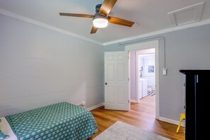 A bedroom with a bed, a ceiling fan, a door leading to another room, and a small black cabinet. - Quiet Country Living Near Whiteville (Whiteville)