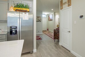 A kitchen with a refrigerator, a water dispenser, and a wooden shelf with plants.