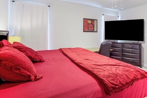 Un dormitorio con una cama grande, un aparador, un televisor y un cuadro en la pared.