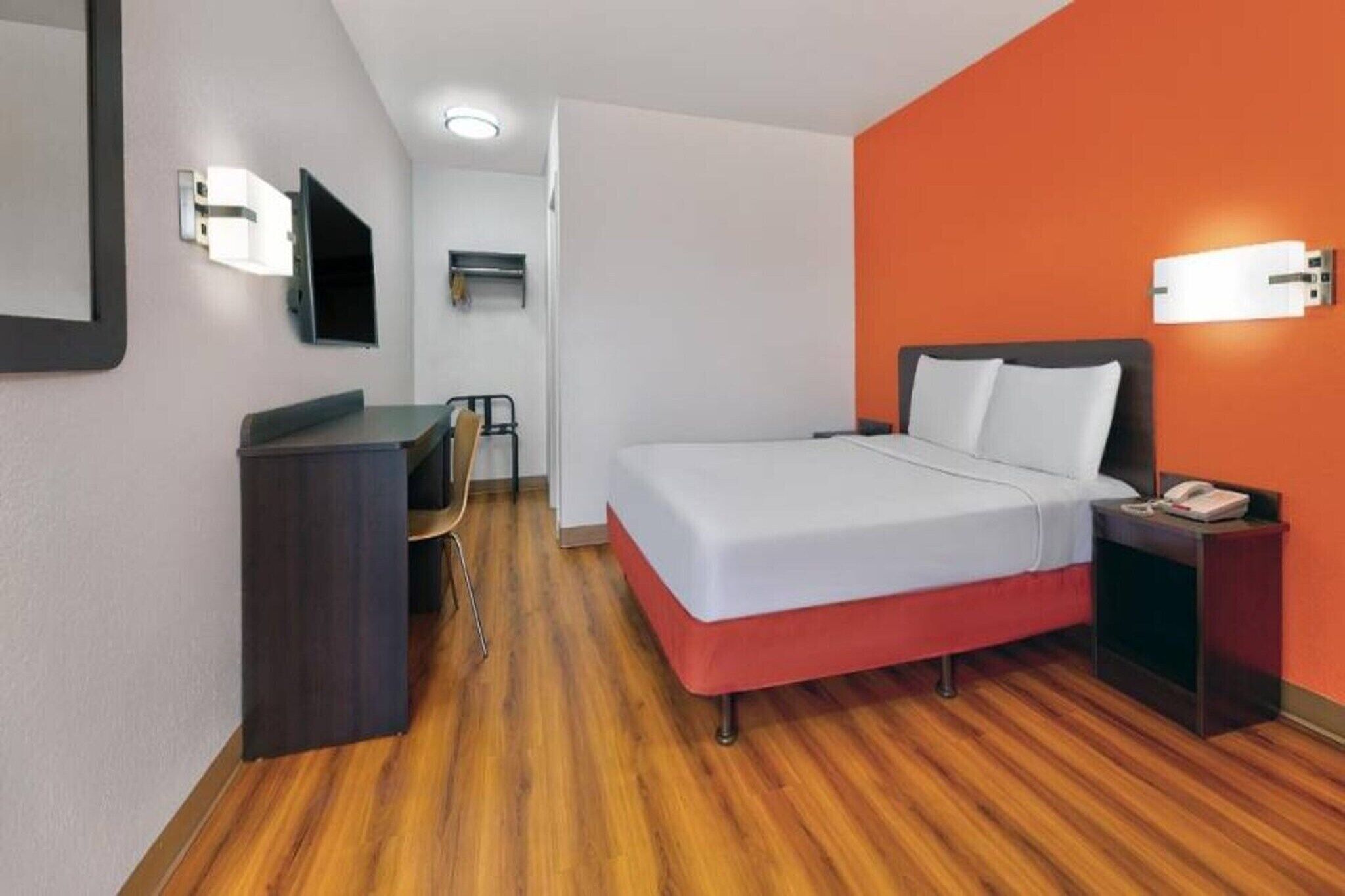 Ein Hotelzimmer mit Bett, Schreibtisch, Stuhl und Fernseher.