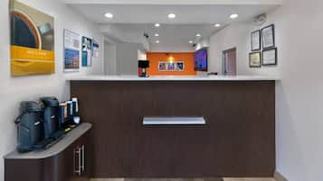 Een receptie met een balie, koffieautomaten en ingelijste certificaten aan de muur.