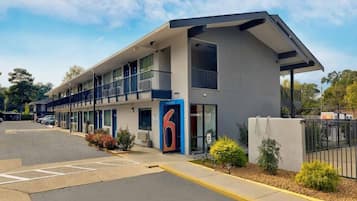 Een motel met een modern ontwerp, met een ruime entree, meerdere balkons en een parkeerplaats.