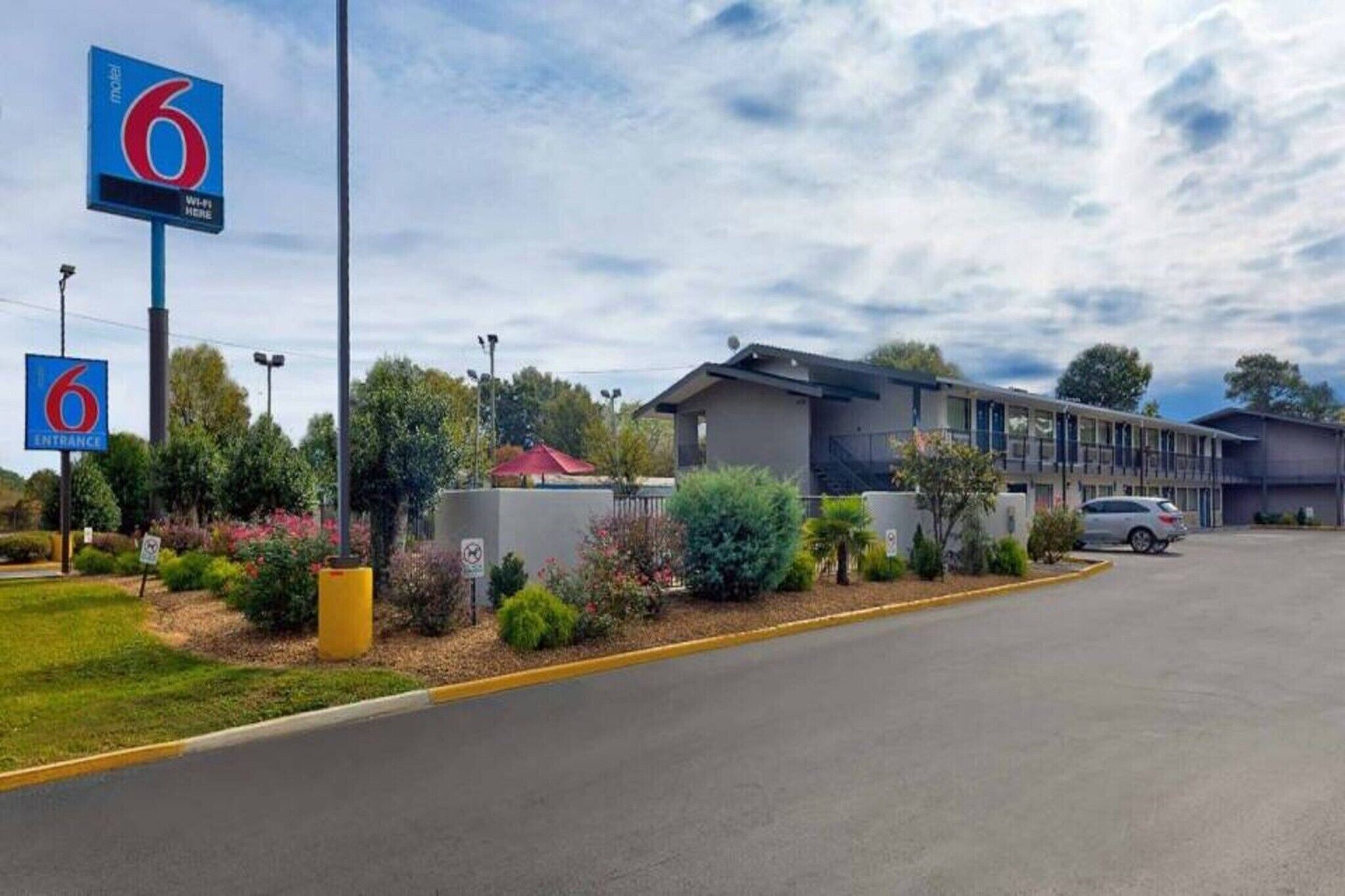 A motel with a clear entrance sign, a parking lot, and a building with a modern design.
