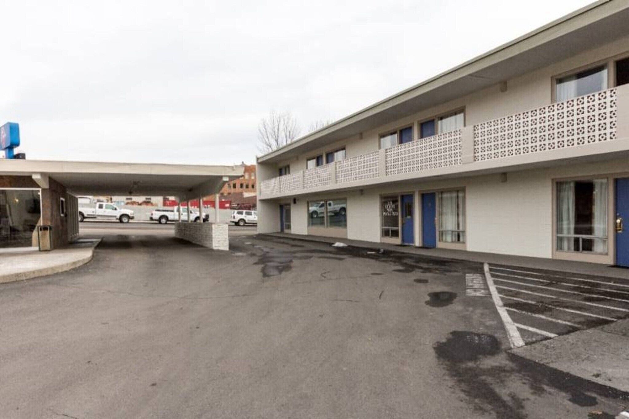 A parking lot with a building featuring a patterned facade and a covered entrance.