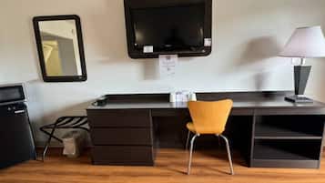 A compact room with a desk, a chair, a television, and a lamp.