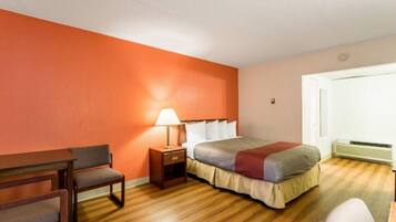 Een hotelkamer met een bed, nachtkastje, lamp, stoel en een verwarming.