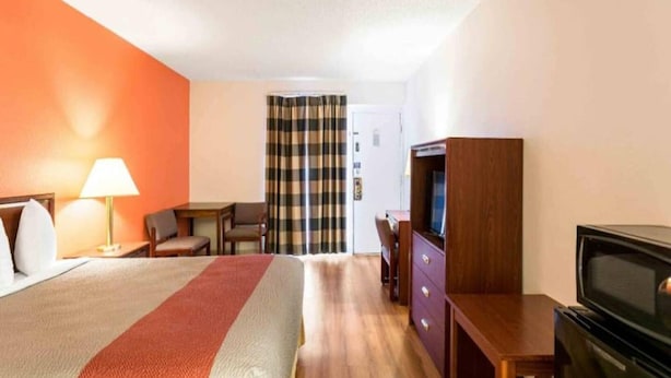 Ett hotellrum med en säng, ett skrivbord, en tv och en garderob.