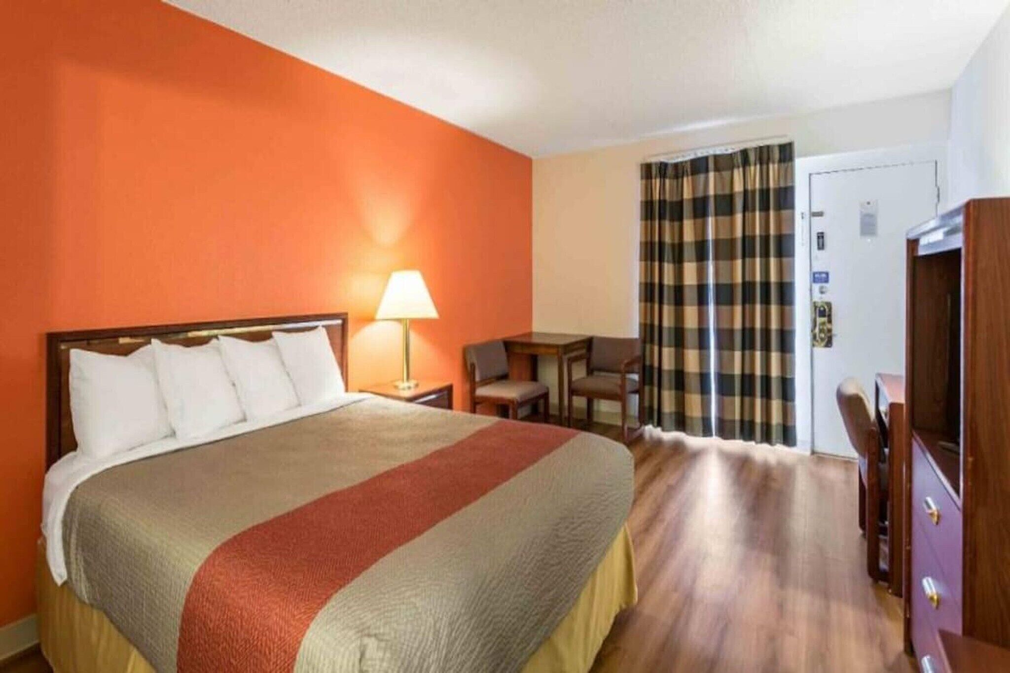A hotel room with a bed, a desk, a chair, and a wardrobe.