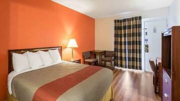 A hotel room with a bed, a desk, a chair, and a wardrobe.