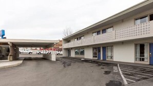 En parkeringsplats med en byggnad som har en slät fasad och ett mönstrat staket.