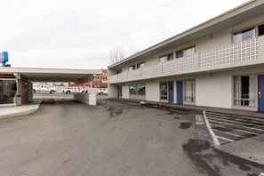 A parking lot with a building featuring a flat facade and a patterned fence. - 1 King Bed | Suite, Non-Smoking, Kitchen (Butte)