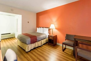 Ein Hotelzimmer mit einem Bett, einem Nachttisch, einem Schreibtisch und einem Sessel.