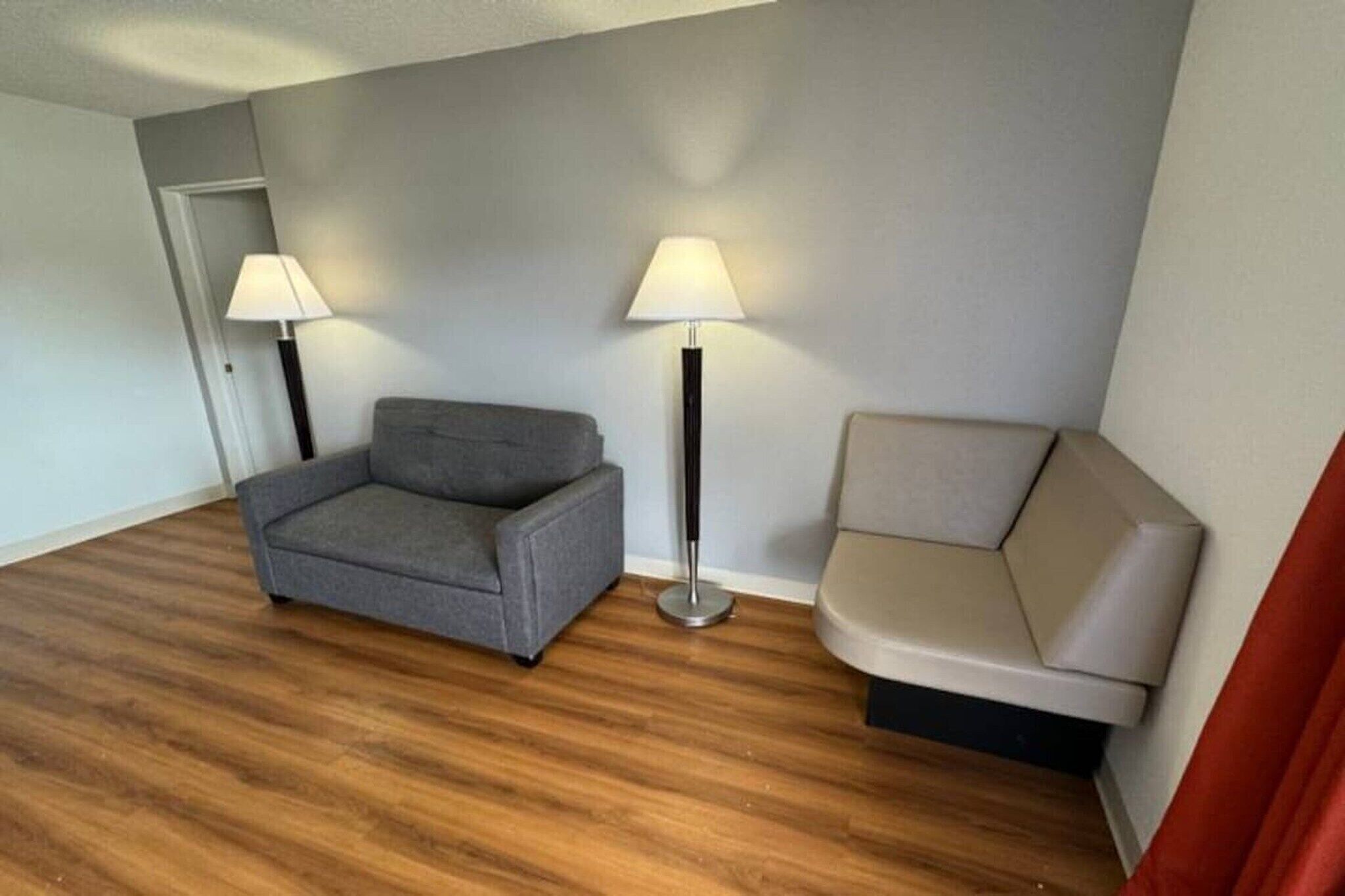 Ett rum med en grå soffa, en beige soffa och två golvlampor.