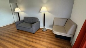 Ett rum med en grå soffa, en beige soffa och två golvlampor.