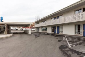 A parking lot with a building featuring a flat facade and a covered entrance. - 1 Queen Bed | Non-Smoking, Micfridge (Butte)