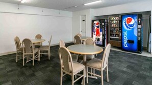 A conference room with round tables and chairs, a white door, and two Pepsi vending machines. - 1 Queen Bed | Non-Smoking, Micfridge (Butte)