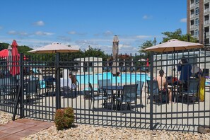Ein Poolbereich im Freien, umzäumt mit Liegestühlen und Sonnenschirmen.