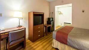 Ett hotellrum med en säng, ett skrivbord, en tv och ett litet pentry.