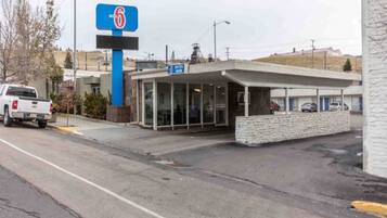 A motel with a prominent sign, a covered entrance, and a parking area.