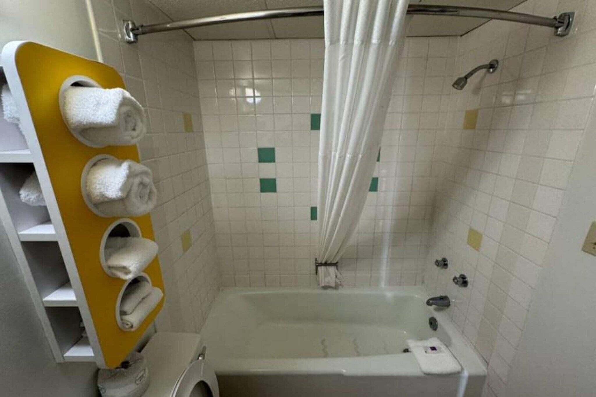 A bathroom with a bathtub, a shower, and a towel rack with multiple towels.