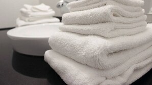 A stack of white towels on a black countertop with a white sink and a mirror in the background. - 2 Queen Beds | Non-Smoking (Rexburg)