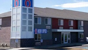 A motel with a prominent '6' sign, a 'NOW OPEN' sign, and a brick facade. - 2 Queen Beds | Non-Smoking (Rexburg)