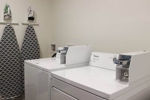 Ein Waschbereich mit zwei Whirlpool-Waschmaschinen, einem gemusterten Handtuchhalter und einer kleinen Ablage mit Gegenständen.