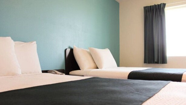 A hotel room with two beds, a nightstand, and a window with curtains. - 2 Queen Beds | Non-Smoking (Rexburg)