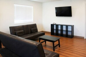 Una sala de estar con un sofá, una mesa de centro, un televisor y un armario.