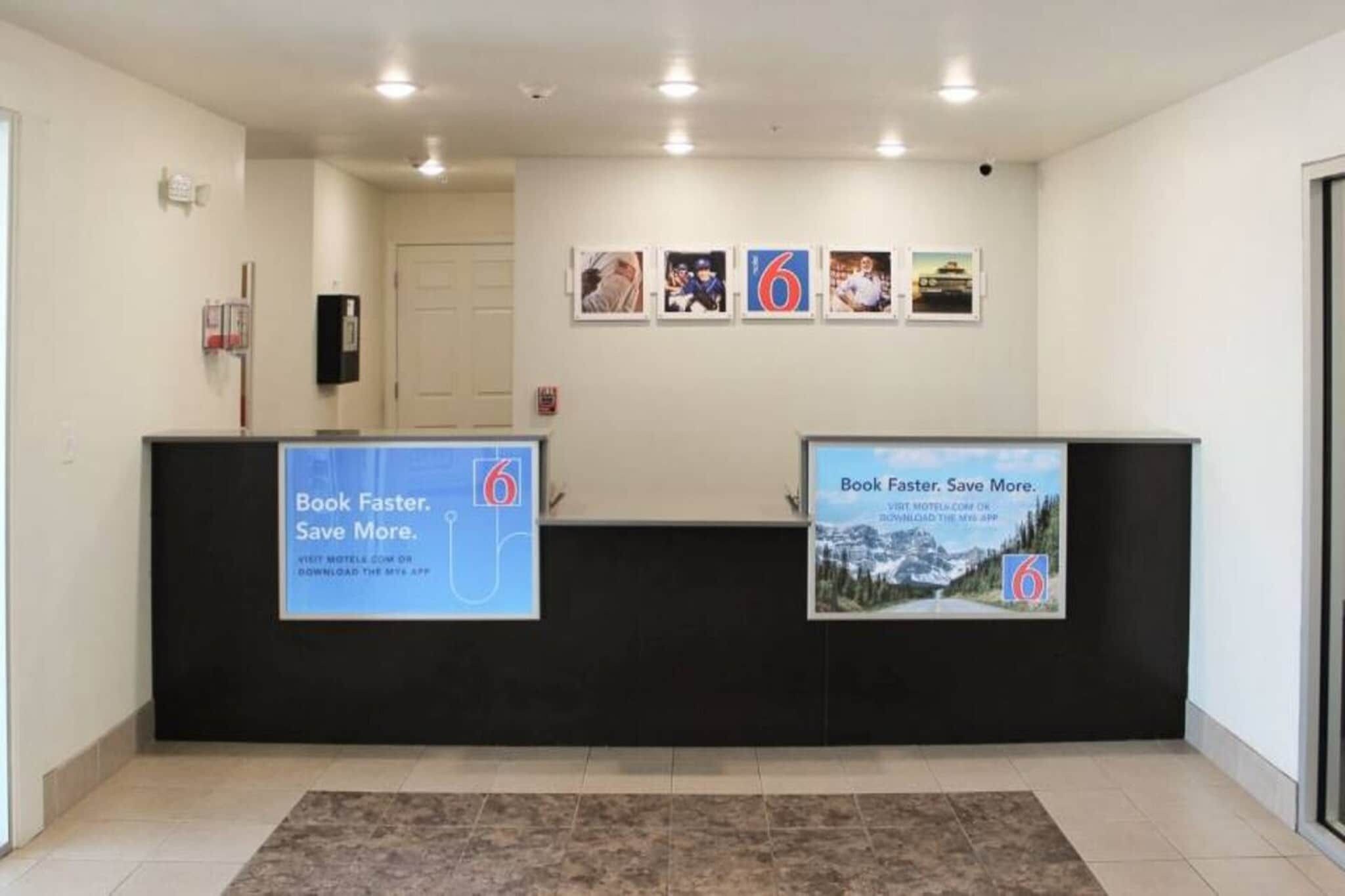 A reception area with a black counter, a large blue sign promoting a reading app, and a series of framed pictures on the wall.