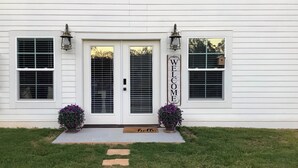 A white house with a front door, two potted plants, a welcome sign, and a birdhouse on the window. - Hot Tub, Goats, 10 Mins to Sheriff's Jeep Fest! (Dawsonville)