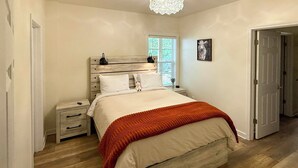 A bedroom with a wooden headboard, a bed with white bedding and an orange throw, a nightstand with a lamp, and a window with blinds. - Hot Tub, Goats, 10 Mins to Sheriff's Jeep Fest! (Dawsonville)