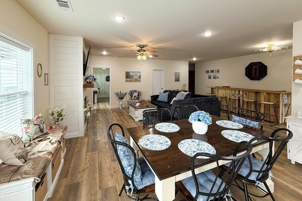 A dining area with a wooden table, blue patterned placemats, and black chairs.