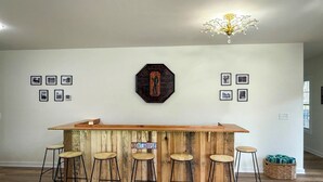 A bar area with a wooden counter and stools, a sign reading 'GOAL HOUSE', and framed pictures on the wall. - Hot Tub, Goats, 10 Mins to Sheriff's Jeep Fest! (Dawsonville)