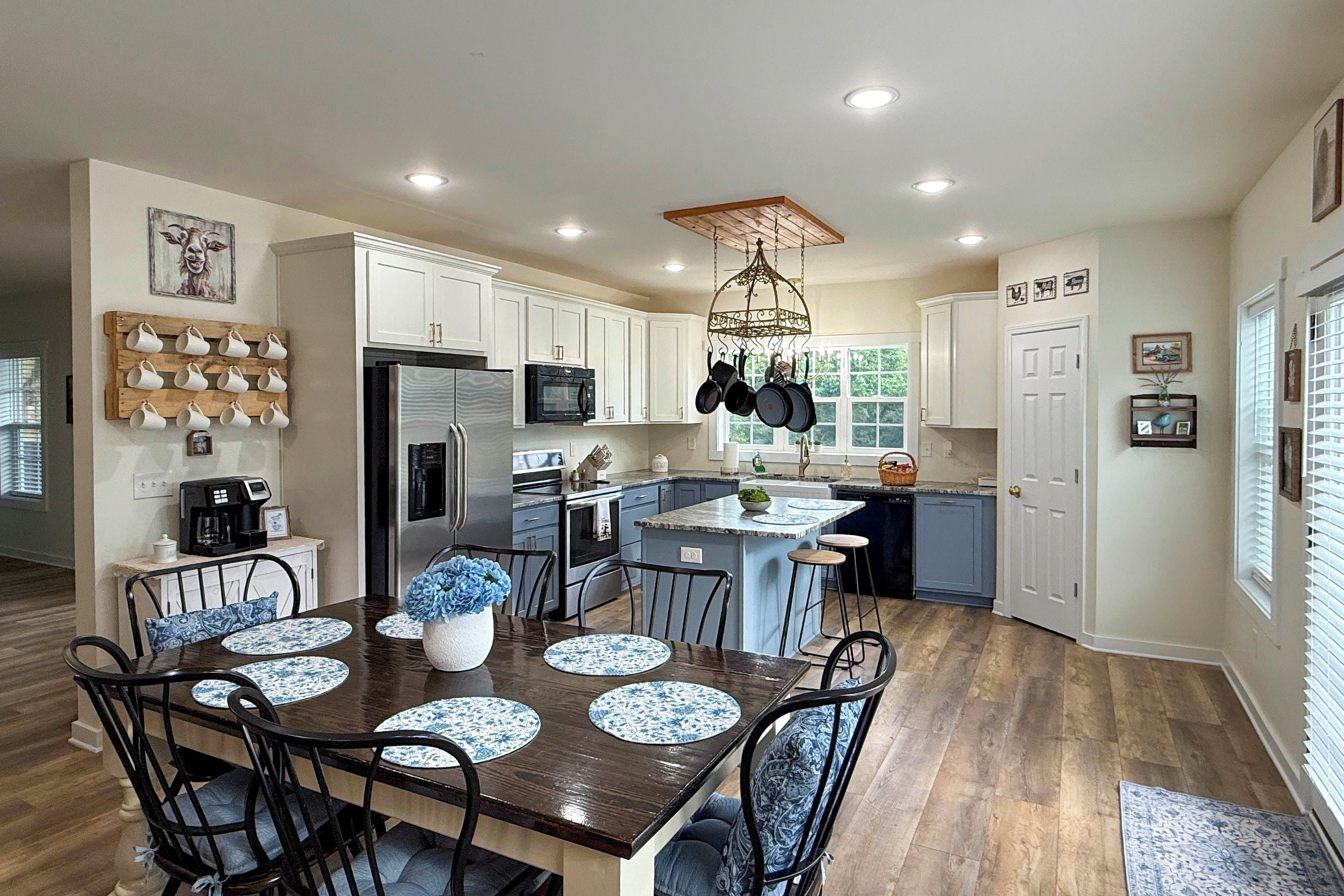A modern kitchen with white cabinets, a central island, and a dining area with a wooden table and blue-patterned placemats.