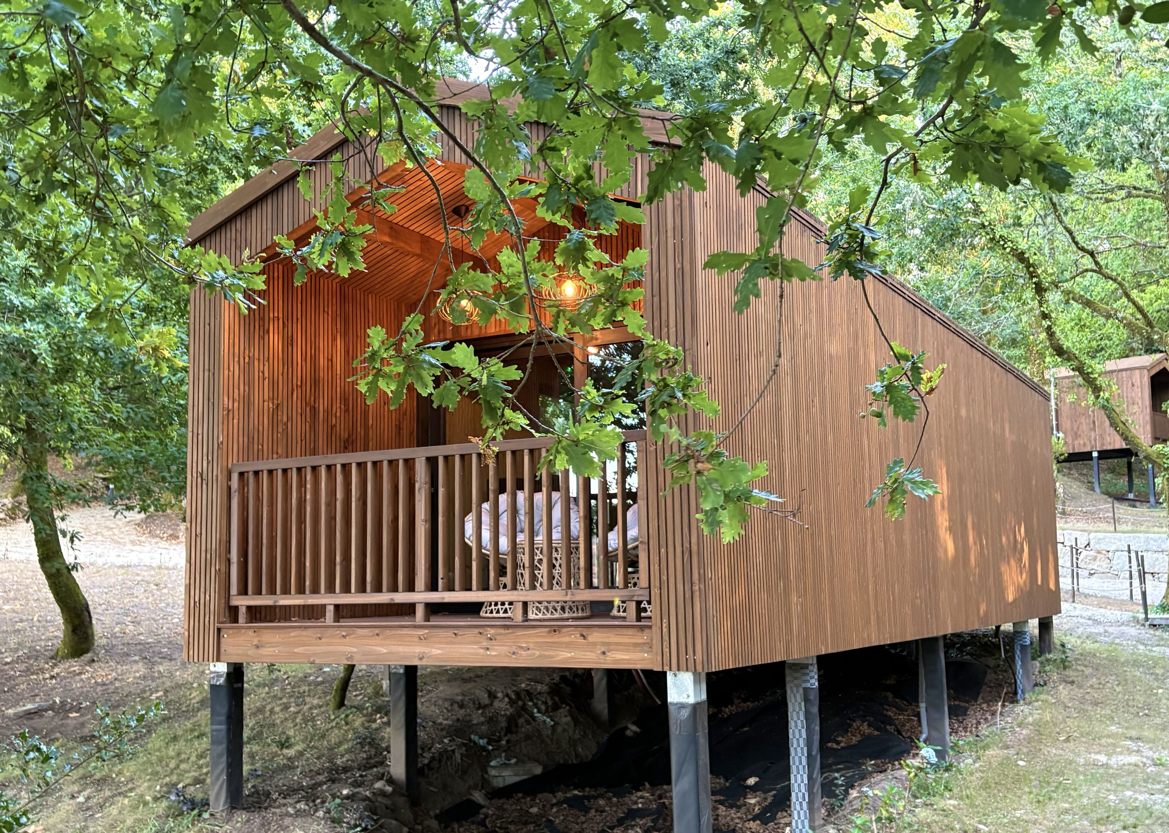 Een houten boomhut met een balkon, omringd door bomen.