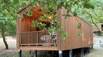 Een houten boomhut met een balkon, omringd door bomen.