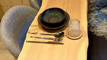 Una mesa de madera con cubiertos y una copa.
