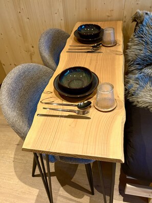 Uma mesa de jantar de madeira com talheres e um copo.