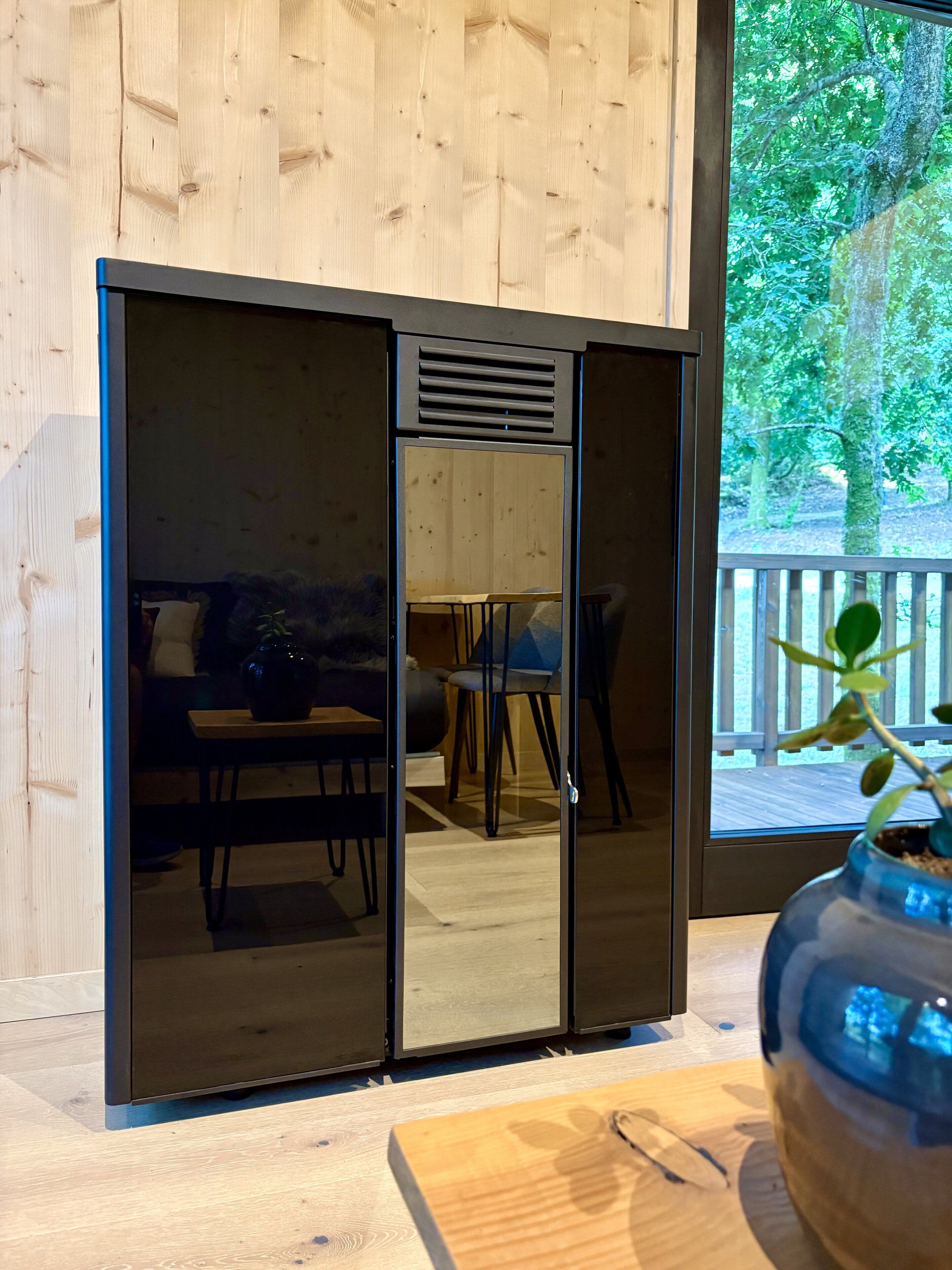 A room with a sliding door leading to an outdoor area, a wooden table, and a potted plant.