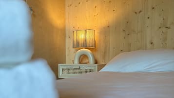 Une chambre d’hôtel avec un mur en bois, une lampe de chevet, un lit avec du linge de lit blanc et une table de chevet avec une lampe.