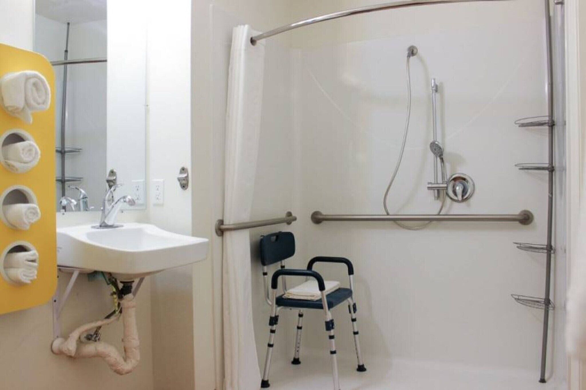 Ein Badezimmer mit Dusche, Waschbecken und einem Stuhl.