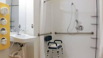 Ein Badezimmer mit Dusche, Waschbecken und einem Stuhl.